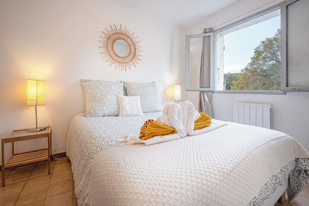A hotel room with a bed, two bedside lamps, a window, and a wall decoration.