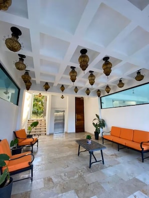 Eine geräumige Lobby mit hoher Decke, einem Musterfliesenfußboden und einer Sitzecke mit orangefarbenen Sofas und Sesseln.