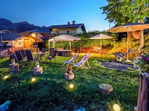 A well-lit outdoor area with lounge chairs, umbrellas, and a dining setup.