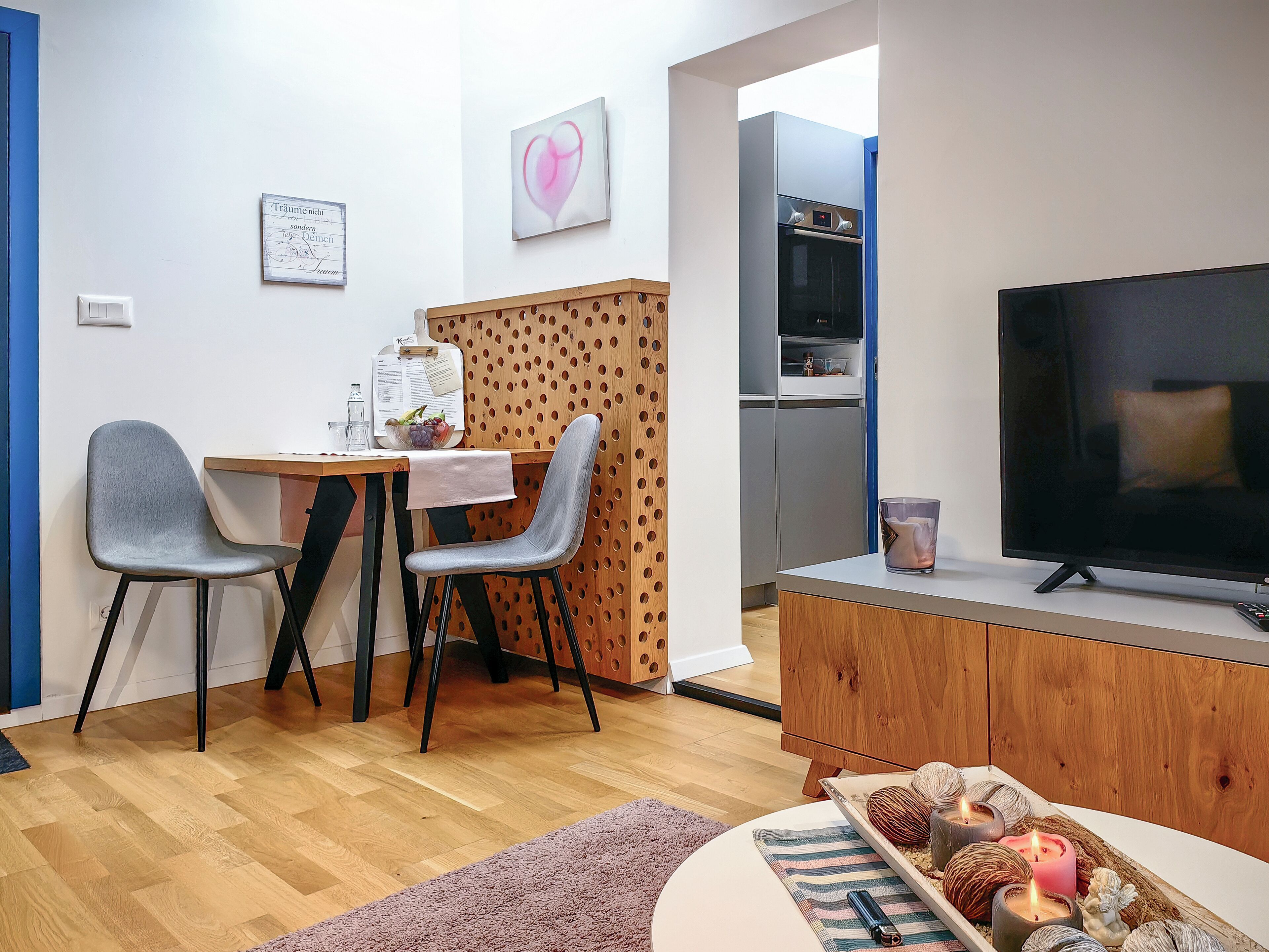 Ein modernes Wohnzimmer mit Essbereich, einem Flachbildfernseher und einer Holzkommode.