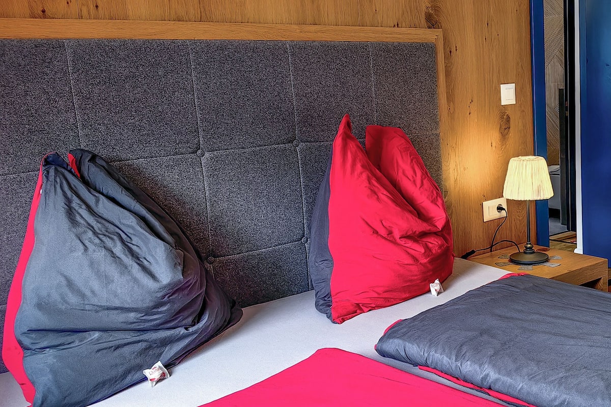 A room with a bed, a nightstand with a lamp, and a wooden door.