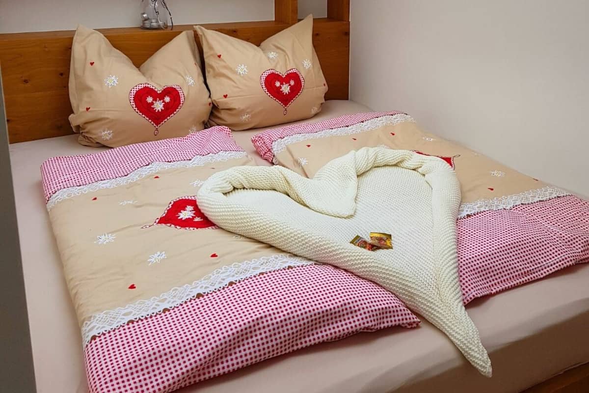 A bedroom with a skylight, a wooden headboard, and a bed with a checkered bedspread and a knitted blanket.