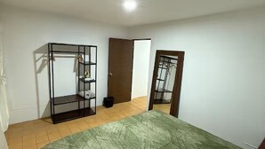 Et soveværelse med seng, garderobe og dør.
