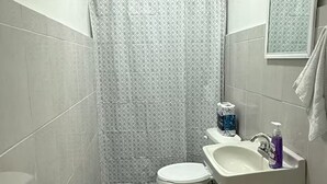 Et badeværelse med toilet, vask og badeforhæng.