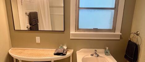 A bathroom with a vanity, two sinks, a window, and a mirror.