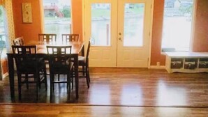Un comedor con mesa y sillas de madera, una puerta blanca y un banco.