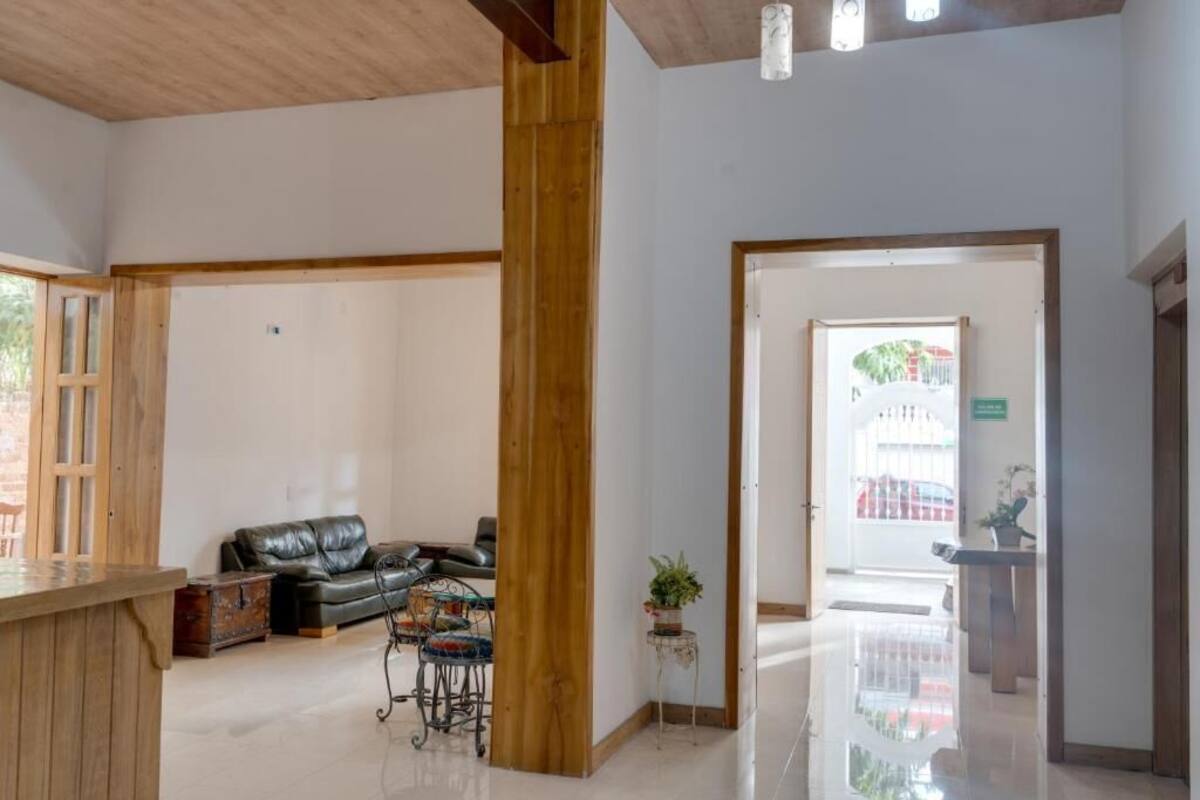 Un vestíbulo amplio con mostrador de recepción de madera, un sofá de cuero negro y una pequeña mesa con una planta.