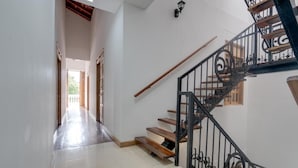 A staircase with a black metal railing, a wooden handrail, and a light fixture on the wall. - Hotel Granada Embassy (Cali)