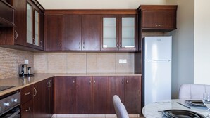 Eine moderne Küche mit dunklen Holzausbau, einem Edelstahlkühlschrank und einem Esstisch aus Marmor.