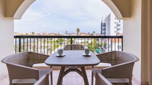 Ein Balkon mit Tisch und Stühlen mit Blick auf eine Stadtlandschaft aus Gebäuden und einem klaren Himmel.