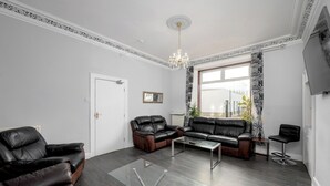 Ein modernes Wohnzimmer mit Ledersofas, einem Glastisch und einer Kristallleuchtre.