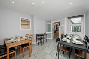 A dining area with two tables, chairs, and a kitchen in the background. - Charming Spacious Guesthouse, Edinburgh - Pass the Keys (Edinburgh)