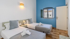 Et hotelværelse med to senge, et natbord, en væglampe og en dør.