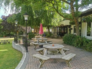 Un patio aménagé avec des tables de pique-nique, un lampadaire et un espace salon abrité.