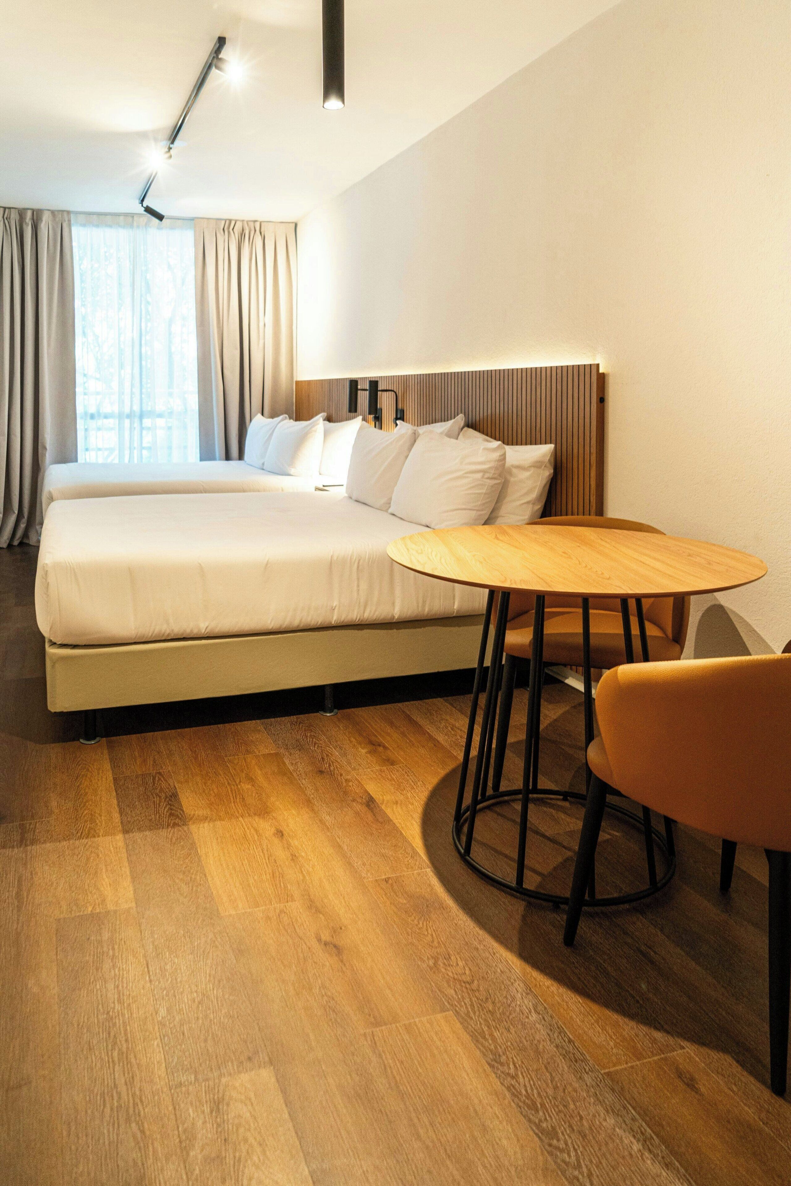 Ein Hotelzimmer mit einem Bett, einem runden Holztisch und einem Stuhl.