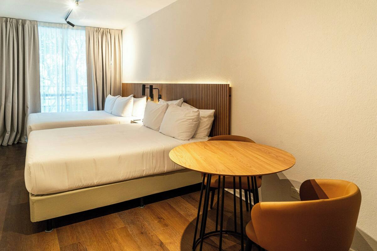 Habitación de hotel con cama doble, una mesita redonda y una silla.