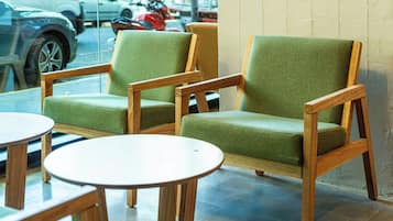 A seating area with two green upholstered chairs and two round wooden tables.