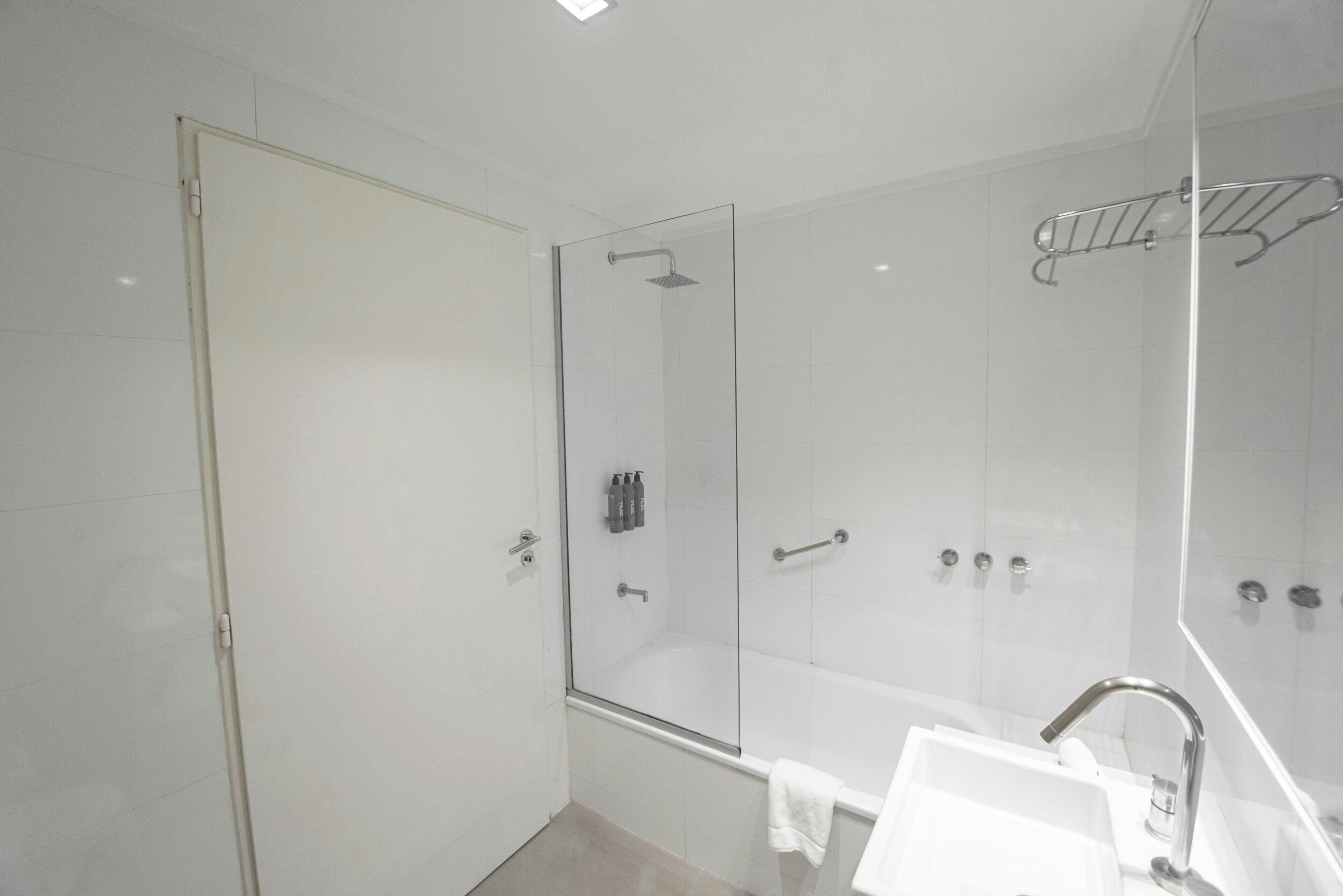 Une salle de bain moderne avec une douche à parois de verre, un lavabo blanc et un miroir.