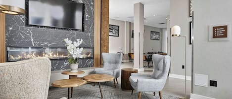 A modern living room with a fireplace, comfortable seating, and a flat-screen TV mounted on the wall.