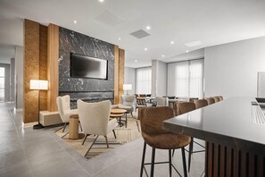 Un moderno vestíbulo de hotel con una televisión de pantalla plana, asientos cómodos, una zona de bar y una chimenea.