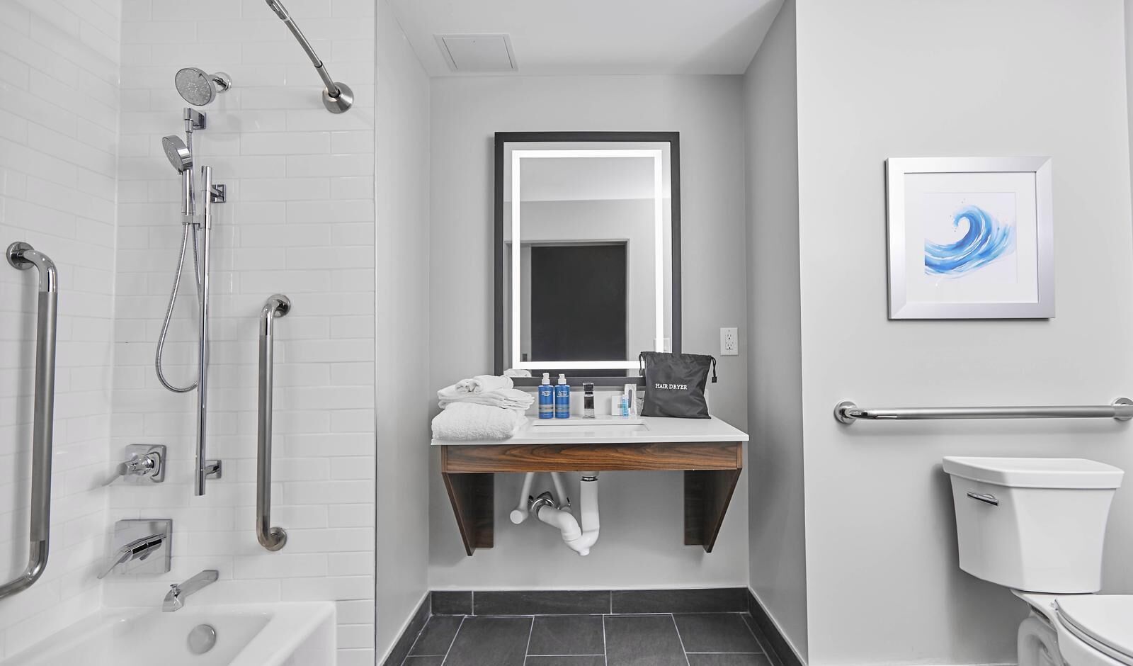 A modern bathroom with a shower, toilet, sink, and a framed artwork on the wall.
