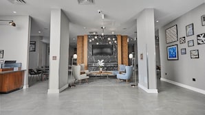 A modern hotel lobby with a reception desk, seating area, and a large TV screen. - Four Points By Sheraton Oakville (Oakville)
