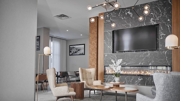 A modern living room with a fireplace, a flat-screen TV, and a dining area. - Four Points By Sheraton Oakville (Oakville)