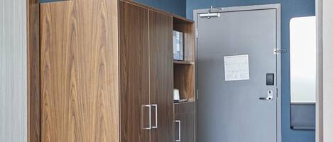 Une pièce avec une armoire en bois, une porte sur laquelle est affiché un avis et un luminaire au plafond.