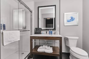 Un baño moderno con cabina de ducha de vidrio, tocador con espejo y inodoro.