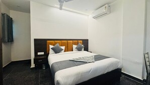A hotel room with a bed, a nightstand, a wall-mounted air conditioner, and a ceiling fan. - Vaayu Homestay (New Delhi)