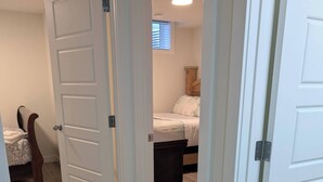 A bedroom with a bed, a nightstand, and a wooden headboard. - 2 Bedroom Guest Suite in SW (Calgary)