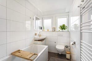 Een moderne badkamer met een bad, toilet en wastafel.