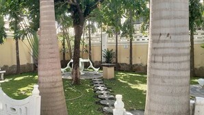 Un giardino con palme, un recinto bianco e un sentiero in pietra.