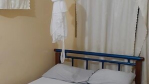 Un letto singolo con struttura in metallo blu, biancheria da letto bianca e una zanzariera appesa sopra.
