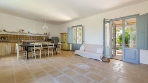 A spacious kitchen with a dining area, a sofa, and a view through open doors. - Casa Agata by BarbarHouse (Ruffano)