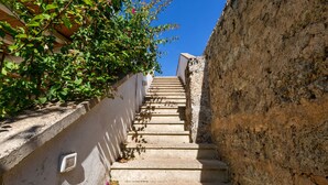 A stone staircase leading up a hill, surrounded by greenery and a clear blue sky. - Casa Agata by BarbarHouse (Ruffano)