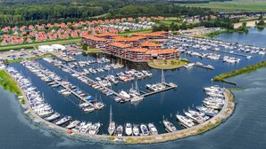 Vista aérea de un puerto deportivo con numerosas embarcaciones amarradas, rodeado de edificios residenciales con techos rojos.