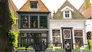 Una hilera de edificios de arquitectura tradicional, incluyendo un restaurante llamado 'Ratatouille' y una tienda llamada 'PROEF & KOOKLOKAAL'.