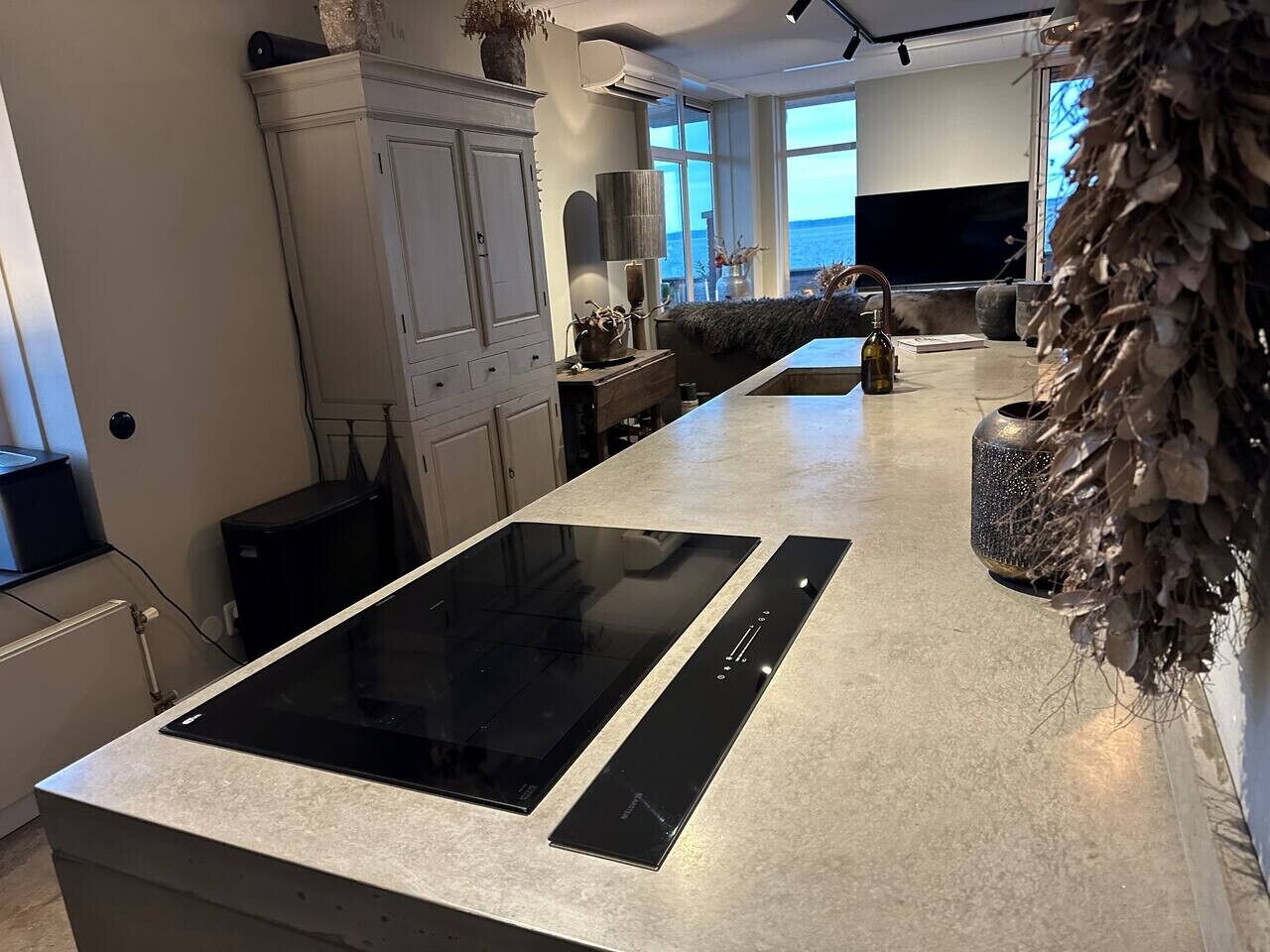Una cocina moderna con una isla grande, electrodomésticos integrados y vista al mar.