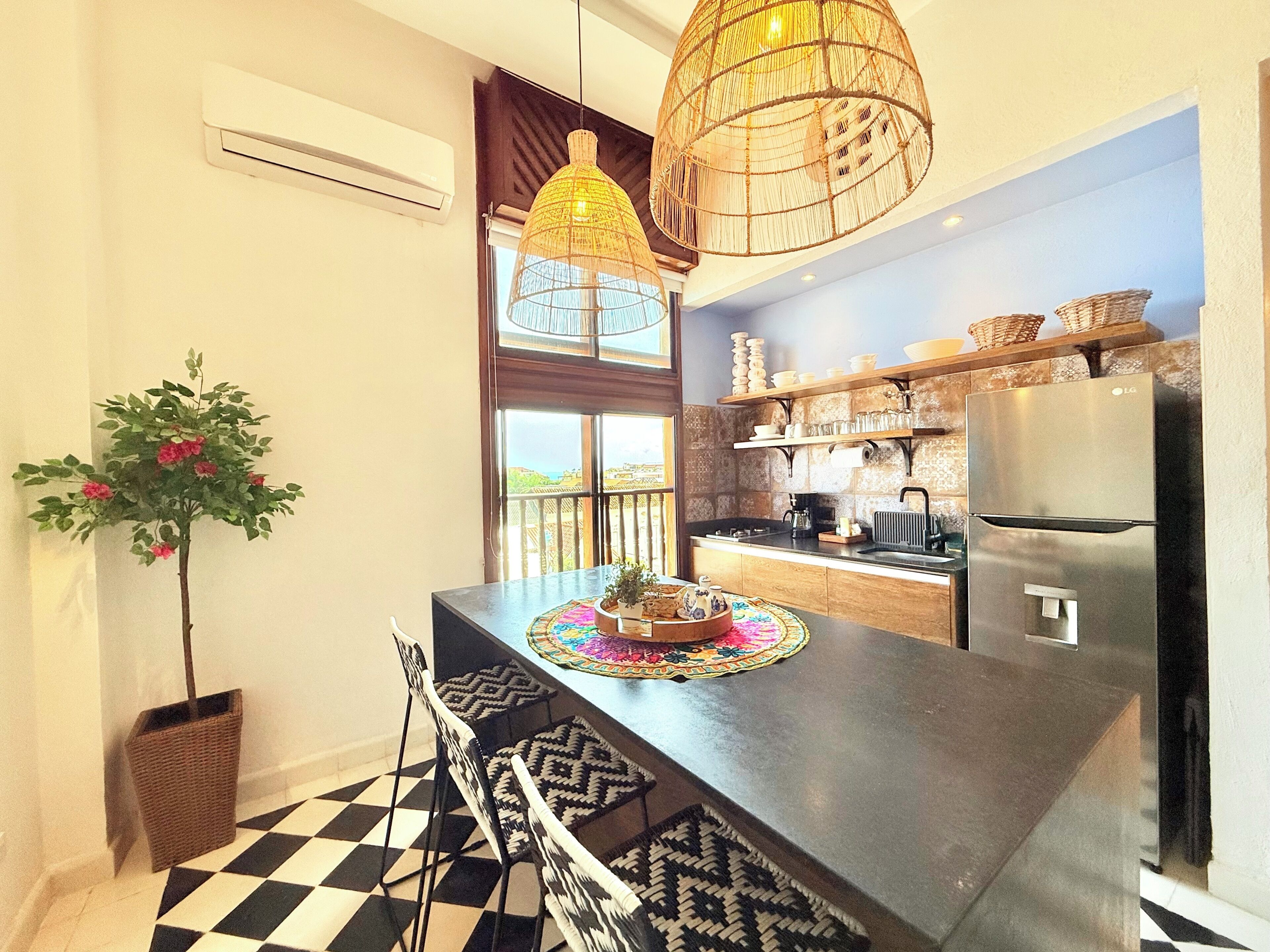 A kitchen with a central island, a refrigerator, and a hanging light fixture.