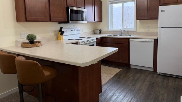 Una cocina con armarios de madera, microondas, estufa, lavavajillas y una ventana.
