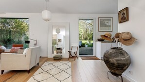 Una sala moderna con un sofá, un tapete, un jarrón grande y vistas al exterior.