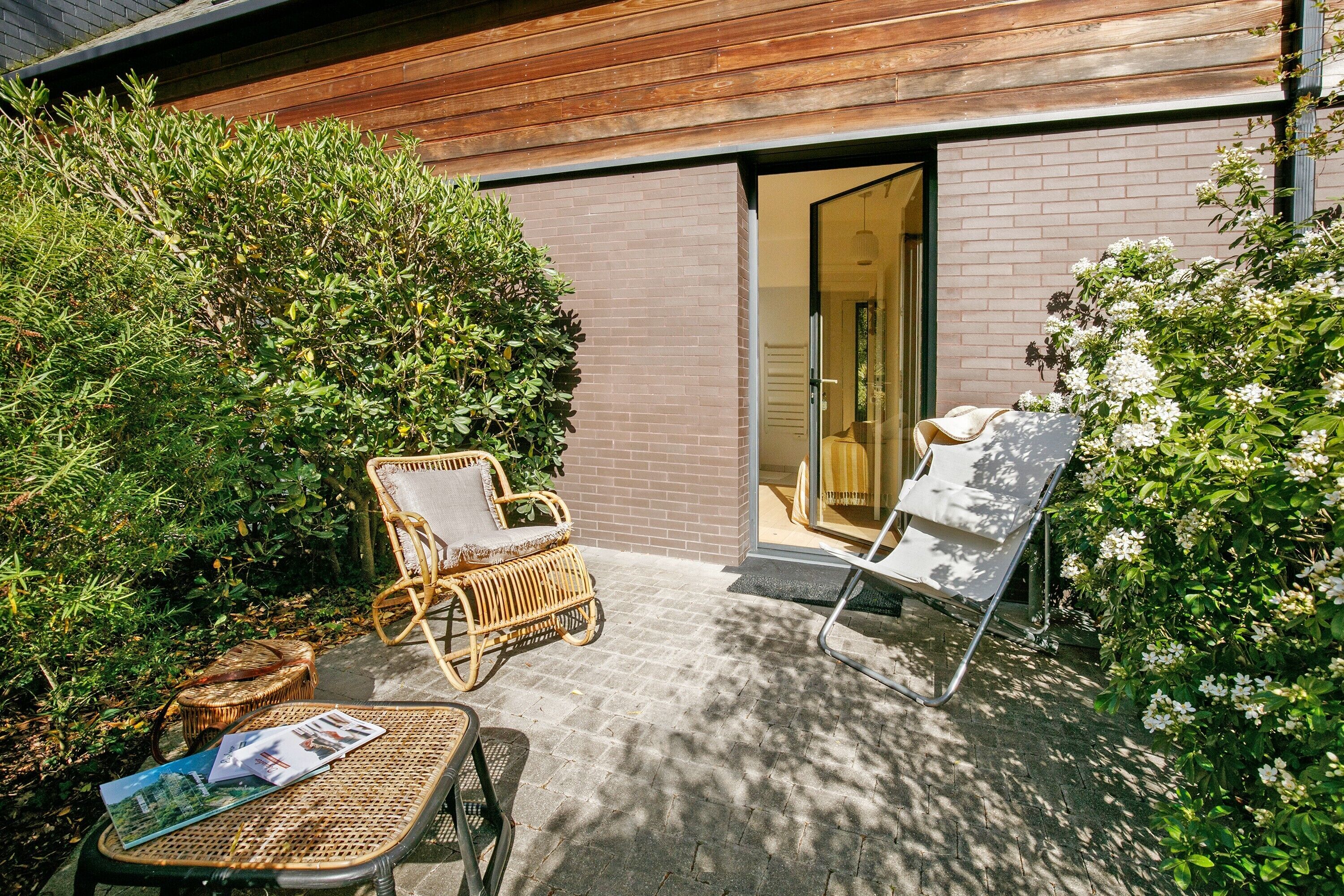 An outdoor patio area with wicker furniture, a magazine, and a door leading to a room.
