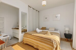 Ein Hotelzimmer mit einem Bett, einem Schreibtisch, einem Sessel, einem Spiegel, einem Nachttisch und einer Lampe.