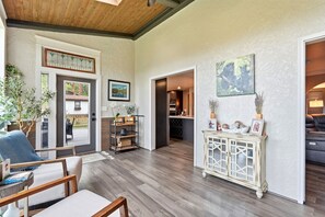A spacious living area with a wooden ceiling, a dining area with a table and chairs, a kitchen with modern appliances, and a hallway leading to another room. - Spacious Colorado Retreat, Game Room, Solarium, Patios & Mountain View’s (Evergreen)