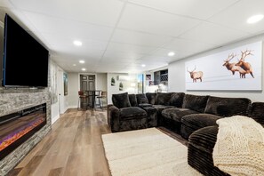 A modern living room with a fireplace, comfortable seating, and a large TV. - Spacious Colorado Retreat, Game Room, Solarium, Patios & Mountain View’s (Evergreen)
