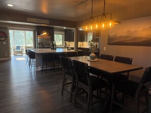 Una cocina moderna con una isla central, mesa de comedor de madera oscura y sillas.