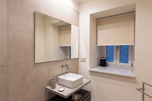 A modern bathroom with a large mirror, a white sink, a window with blinds, and a coffee maker on the windowsill. - Partenope SeaFront Double Rooms-Luxury design (Napoli)
