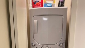 Un lave-linge compact et blanc, doté d’un panneau de commande, installé dans un espace étroit entre deux murs.