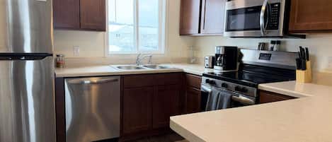 Una cocina moderna con electrodomésticos de acero inoxidable, armarios de madera y un amplio ventanal.